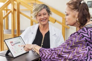 Female occupational therapist helping female resident with reading therapy
