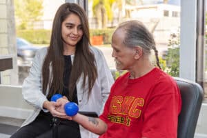 Female physical therapist helping male resident with hand weight