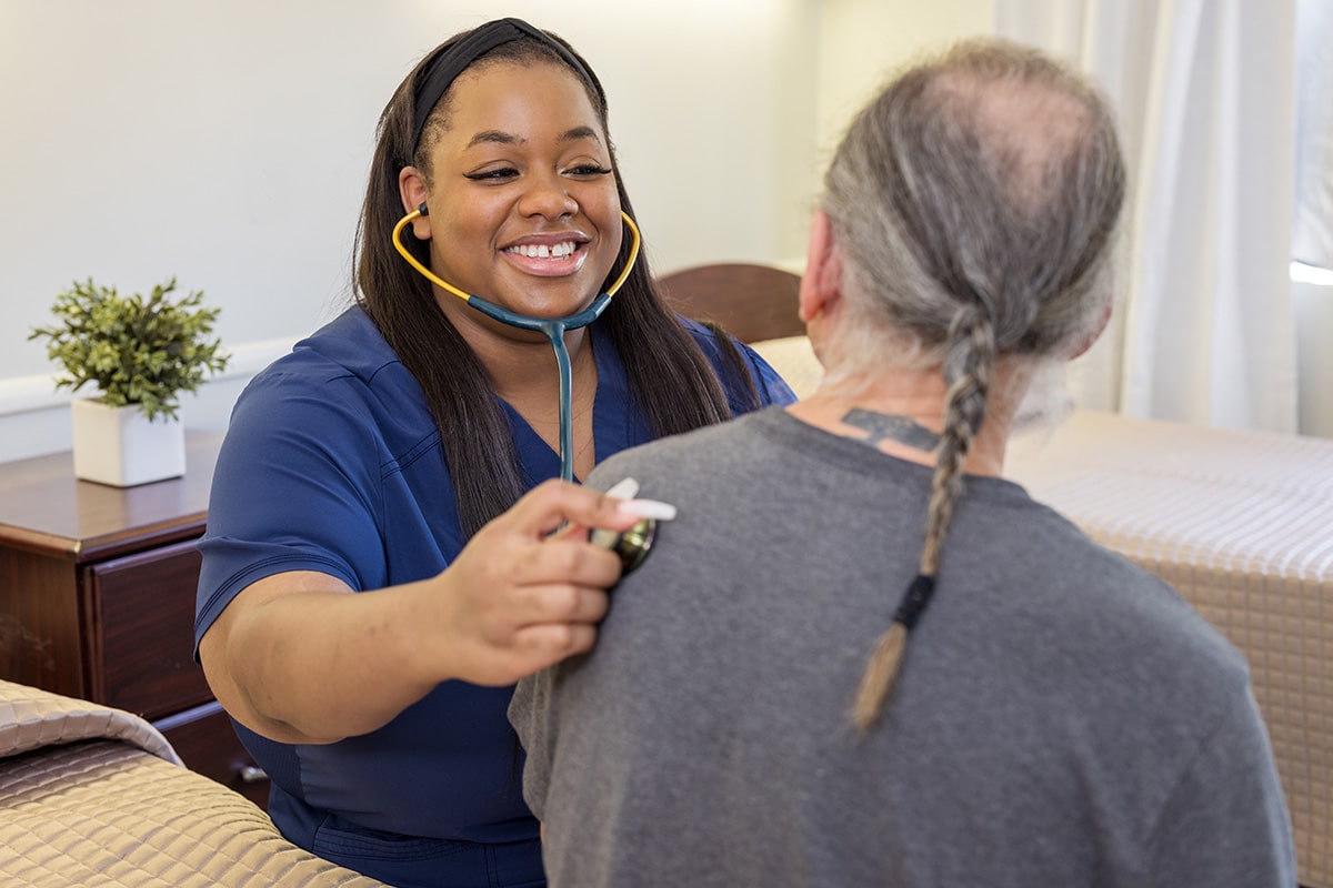 Female nurse with stethescope listening to male resident