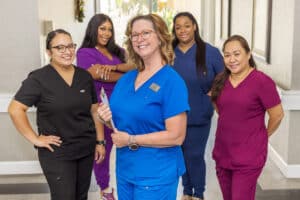 Staff of five nurses in scrubs smiling
