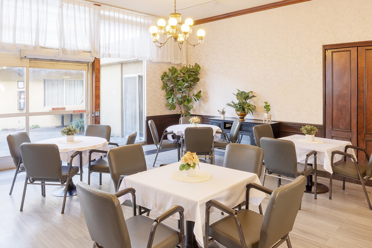 Facility dining room with white tablecloths and flower centerpieces
