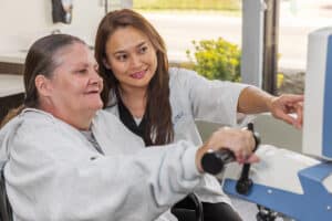 Physical therapist helping woman on stationary bike