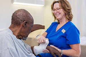 A happy nurse helping Elderly resident with a bandaged wrist